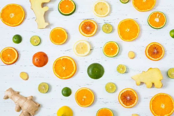 Citrus pattern on white wooden background. Assorted citrus fruits. Slices of orange, tangerine, lemon, lime and ginger. Top view.