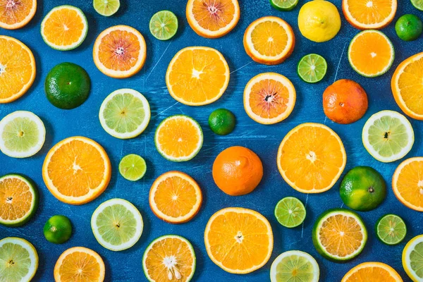 Citrus pattern on blue background. Assorted citrus fruits. Slices of orange, tangerine, lemon, lime. Top view.
