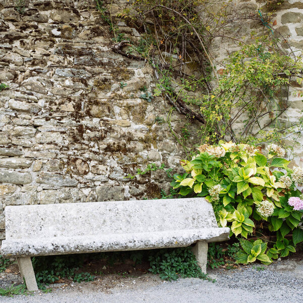 Ancient stone bench in a small village of medieval origin. Volpaia, Tuscany, Italy. Square shape of picture.