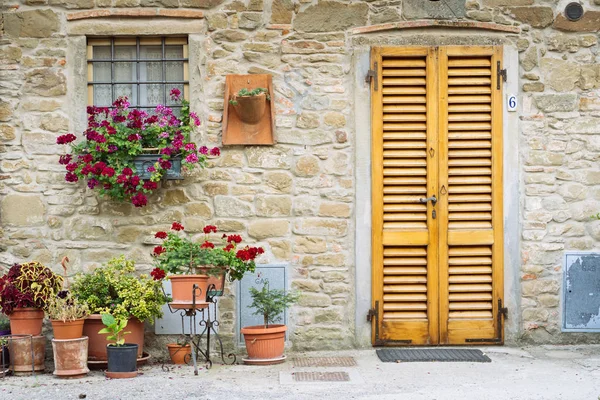 Цветы перед каменной стеной в маленькой деревушке Средневековья. Volpia, Tuscany, Italy — стоковое фото