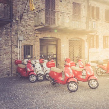 Citta della Pieve, Italy - September 22, 2018: Typical street scene with a red scooters on an old cobblestoned street clipart
