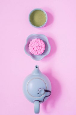 Pembe ay keki, mavi çaydanlık, pembe arka planda bir fincan yeşil çay. Çin sonbahar ortası festival gıda.