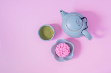 Pembe ay keki, mavi çaydanlık, pembe arka planda bir fincan yeşil çay. Çin sonbahar ortası festival gıda.