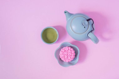 Pink mooncake, blue teapot, cup of green tea on a pink background. Chinese mid-autumn festival food. clipart