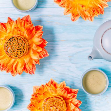 Taze turuncu dahlia çiçek Mooncakes, mavi bir çaydanlık ve mavi ahşap arka plan üzerinde yeşil çay bardak. Çin sonbahar ortası festival gıda.