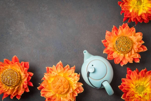 Mooncakes in orange dahlia flowers, teapot and cups of green tea on brown background. Chinese mid-autumn festival food. — Stock Photo, Image