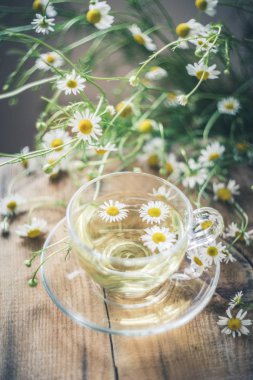 Masasında çiçekler olan bir fincan papatya çayı. Sağlıklı doğal içecek..