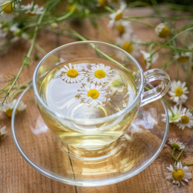 Cup of chamomile herbal tea with flowers on a table. Healthy natural drink. clipart
