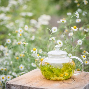Bir masada çiçek ile papatya bitki çayı Çaydanlık. Sağlıklı doğal içecek.