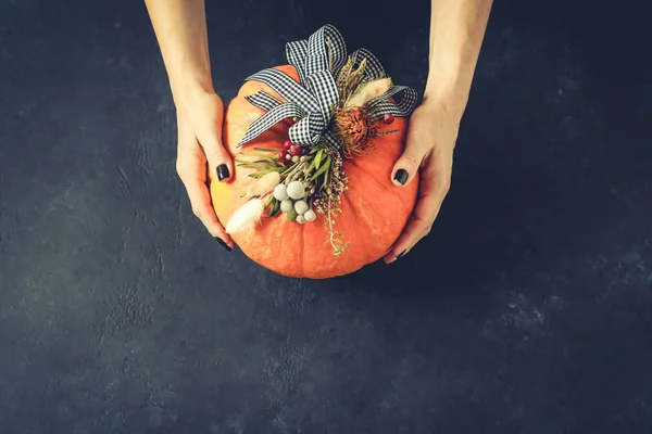 Kvinder hænder holder græskar. Halloween eller Thanksgiving baggrund. Efterårssammensætning i græskar med bånd og tørrede blomster . - Stock-foto