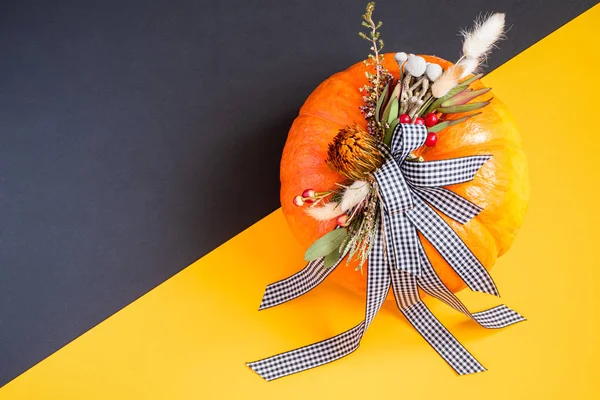 Halloween or Thanksgiving background. Autumn composition in pumpkin with ribbons and dried flowers.