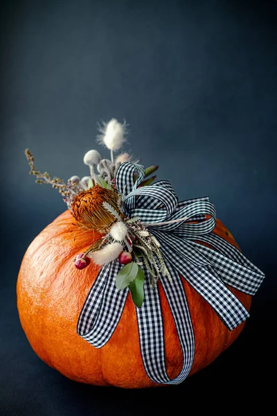 Halloween or Thanksgiving background. Autumn composition in pumpkin with ribbons and dried flowers.