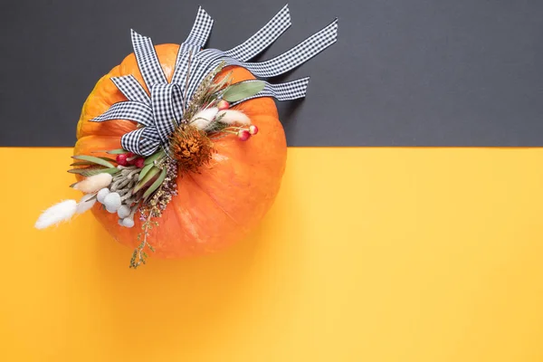 Halloween or Thanksgiving background. Autumn composition in pumpkin with ribbons and dried flowers on duo tone background with copy space.