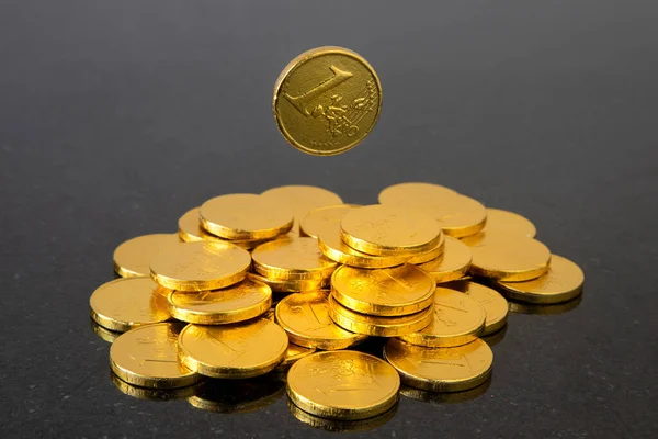 An image of a falling coin.  Gold color, dark background.