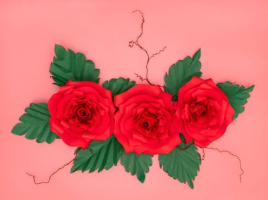 Kırmızı kağıt güller ve somon pembe arka planda kurumuş damarlı küçük beyaz çiçekler..