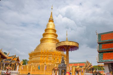Wat Phra Thad Haripunchai 'deki altın bir pagoda yağmur bulutlarına karşı dimdik ayakta duruyor. Kuzey Tayland' ın Lumphum eyaletinde özel olmayan ikonik simgeler oluşturuyor..