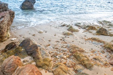 Doğu Tayland 'da doğal bir parkta kayalıklarda güzel kırmızı desenleri olan taşlı bir plaj..