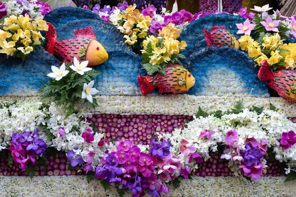 A colorful floral float depicting ocean waves and tropical fish in an annual flower festival parade in Chiang mai, Thailand.