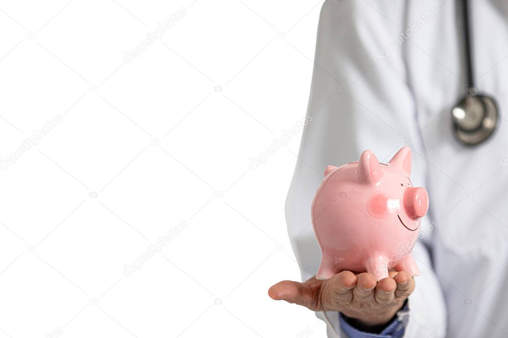 A male doctor in white hospital gown holding a pink piggy bank in his hand. Hospital expense concept.