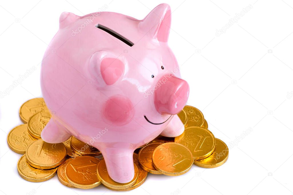 A pink ceramic piggy bank and a pile of simulated gold coins isolated on white background.