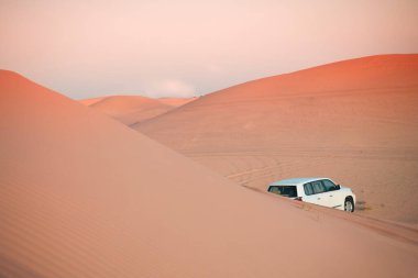 Dubai, Abu Dabi 'de çölde Sunset Safari' de. Al Wathba 'daki SUV arabası akşam ışığı altında egzotik kum tepelerinin arasında tatlı olarak.