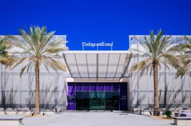 2 Şubat 2015 Abu Dabi, BAE - Manarat Al Saadiyat 'ın güzel dış görünüşüne sahip büyük beyaz modern bina - Çağdaş Kültür ve Sanat Müzesi büyük çöl palmiyeleri ve mavi gökyüzü