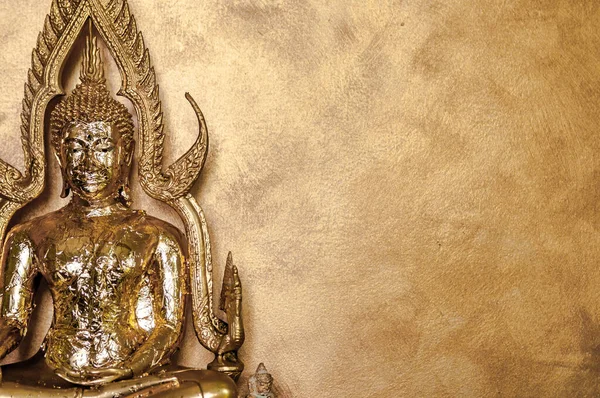 Gold leaves on Buddha Sculpture on goldish wall background - Close up shot