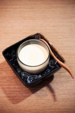 Seramik kasede buzda puding ya da panna cotta, ahşap masada tahta kaşık, yakın çekim.