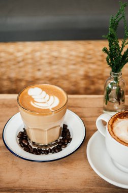 Güzel, sıcak kahve sütlü kahve, üstünde kahve fincanı, ahşap masada kapuçino, yakın çekim.