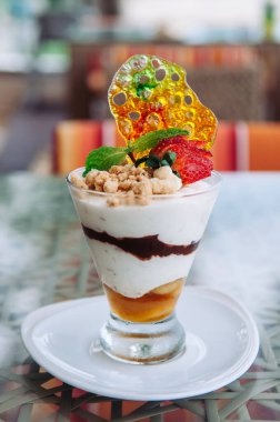 Kremalı, muzlu, karamelli, karamelli ve çilekli beyaz tabakta cam kırıntıları var.