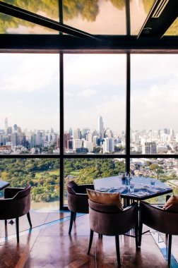 26 AUG, 2013 Bangkok, Tayland - Art deco iç yemek odası, cam duvar Bangkok şehir merkezi manzaralı canlı ayrışma, lüks restoran masası seti ve koltuklar