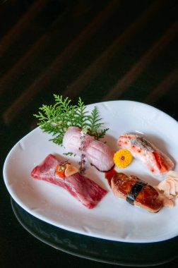 Beyaz tabakta birinci sınıf suşi, foie gras sushi, Otoro sushi, Wagyu sushi, somon suşisi - koyu arkaplan sıcak hava görüntüsü