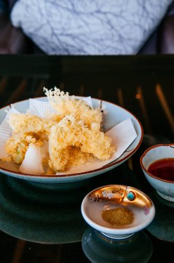 Japonlar sebze ve avokado tempurasını siyah yüzey yemek masasında tuz ve sosla karıştırır.