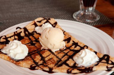 Soğuk vanilyalı krep ve beyaz tabakta çırpılmış krema. Yakın çekim.