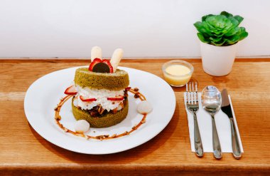 Kremalı, çilekli, yumuşak kek, Mochi ve beyaz tabakta badem karamel soslu.