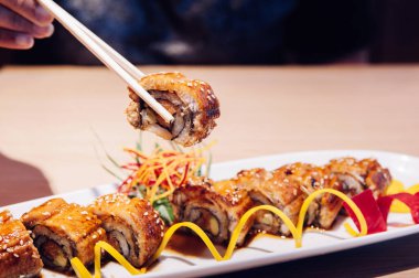 Japon usulü ızgara Unagi Maki sarması ve yemek çubuğuyla yakından çekilen güzel bir parça seçiyorum.