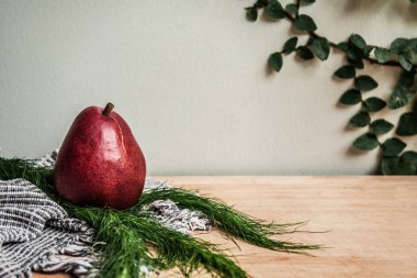 Sağlıklı temalı detoks. Taze kırmızı armut, ahşap tahtada yeşil yapraklı el yapımı kumaş.