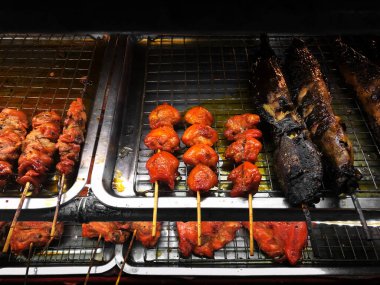 Yağlı ızgara tavuk ve yayın balığı şişi. Bangkok 'ta sağlıksız sokak yemekleri. Yakın çekim.