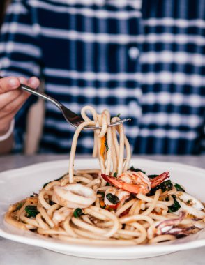 Tayland Pad Cha baharatlı soslu ve gümüş çatallı otlu Bucatini kıvrımlı İtalyan deniz mahsulleri makarnası topluyorum.