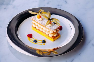 Güzel bir tabak mango çileği Millefeuilles Fransız puf böreği mermer masada zarif bir tabakta