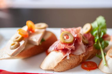 İtalyan aperatifi Carpaccio ekmekleri, Pamaham, foie gras roket marul ve yaban mersini sosu beyaz tabakta.