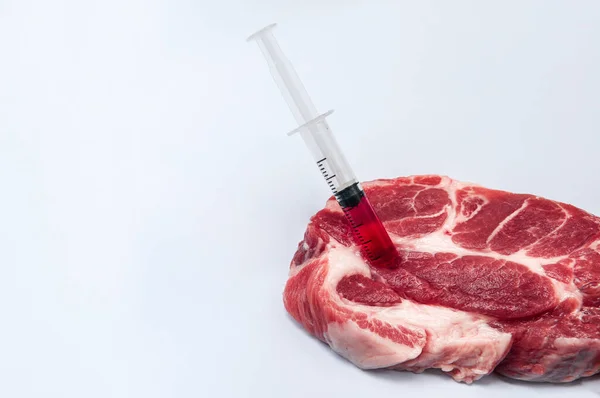 Hormone or Antibiotic contaminated meat - Injecting chemical into raw red meat with syringe isolated on white - Unhealthy food industry