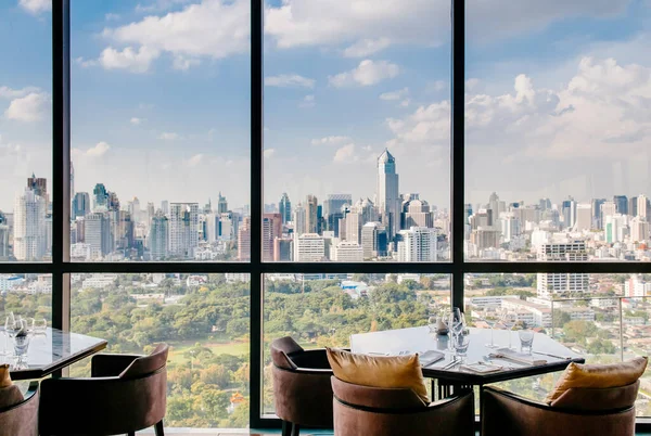 AUG 26, 2013 Bangkok, Thailand - Art deco interior dining room, vibrant desingn with glass wall Bangkok city center view, luxury diner table set and armchairs
