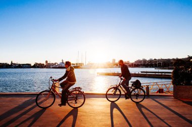 OCT 28, 2012 Valencia - İspanyol çift Valencia Playa de las Arena yakınlarındaki La Marina de Valencia limanında gün batımı manzarasına karşı bisiklet sürüyor