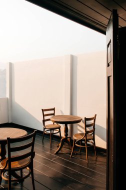 Eski usul ahşap yemek masası ve dışarıdaki balkonda sıcak akşam ışığı altında sandalye.