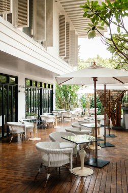 13 MAR 2014 Bangkok, THAILAND - Antika eski rattan sandalyeler yemek masaları ve beyaz şemsiyeler ahşap zemin kattaki balkonda sıcak akşam ışığı altında