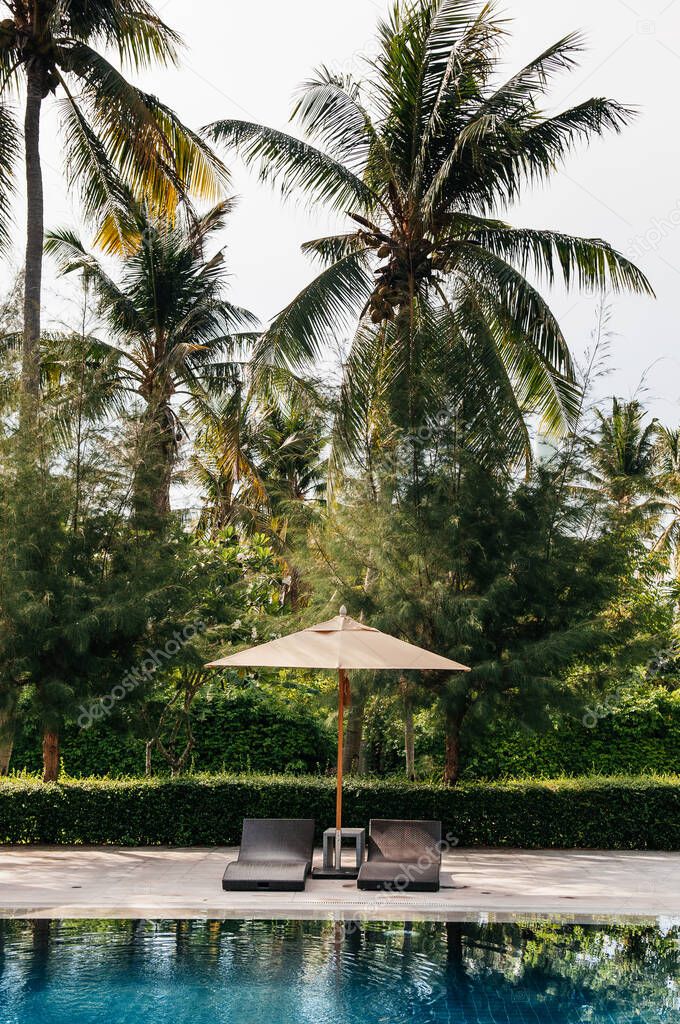 Krabi, THAILAND - Resort pool in tropical coconut garden, umbrellas and pool beds, Koh Lanta tropical resort outdoor space in summer