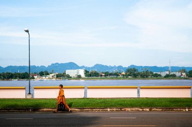SEP 14, 2012 Nakhon Phanom, Tayland - Sarı cüppeli Budist keşiş Nakhon Phanom 'daki Mae Khong nehri boyunca yürüyor. Tayland ve Laos arasındaki doğal sınır. Huzurlu bir manzara