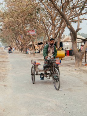 17 Şubat 2012 Dhaka, Bangladeş - Bangladeş halkı ve Dhaka banliyö bölgesindeki toprak yolda trickshaw sürücüsü. Güney Asya 'da işçi sınıfından insanlar
