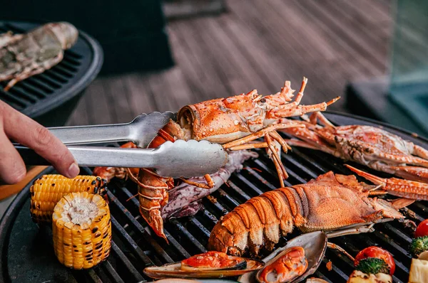 Lobster, rock lobster and mix seafood barbecue cokking on grill - seafood dinner party concept